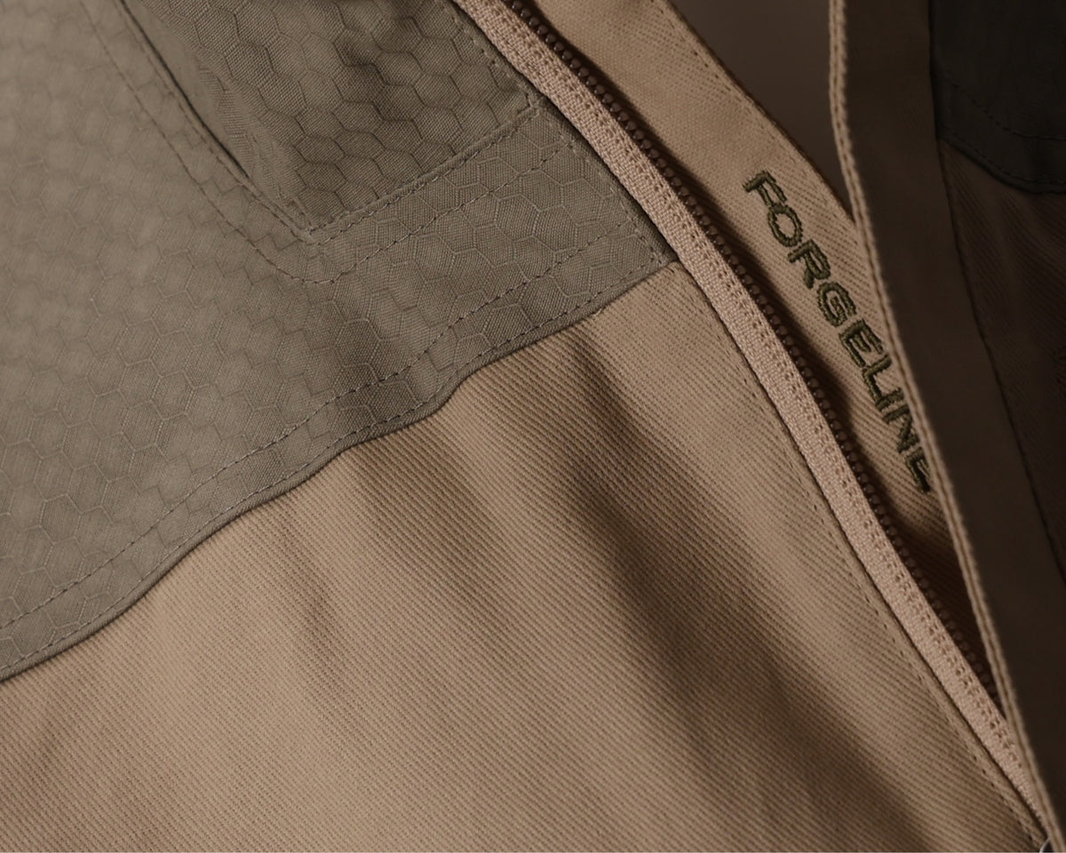 Close-up of a brown dry waxed cotton jacket with a ForgeLine logo on the zipper.